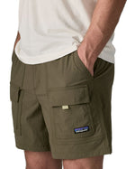 Man wearing Patagonia's men's outdoor everyday shorts in green. With hand in side pocket. Shorts have a loose fit
