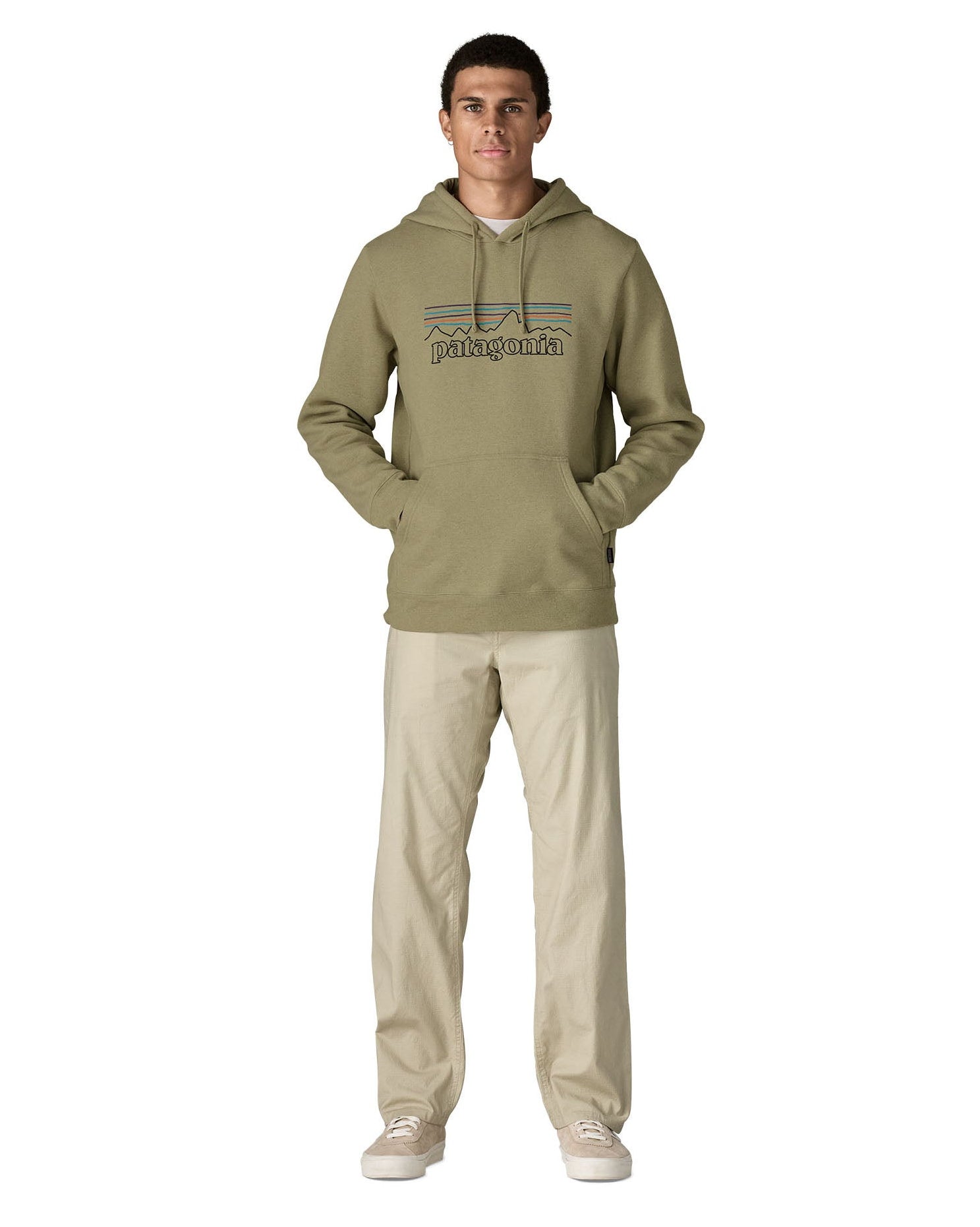 Man wearing Man wearing Patagonia's P-6 Logo Uprisal Hoody in a pale green with the hood down and hands in pouch pockets. Hoody has a relaxed fit