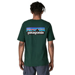 The back of a man wearing the Patagonia men's logo responisbilli tee in cascade green available at Babipur. A short sleeve top in dark green with a large brand patch
