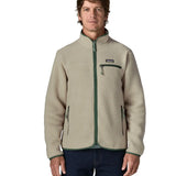 Front of man wearing a Patagonia retro pile jacket in beige with a green trim showing side and chest pockets. Features full front zip
