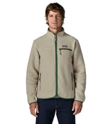 Front of man wearing a Patagonia retro pile jacket in beige with a green trim showing side and chest pockets. Features full front zip