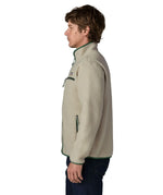 Side of man wearing a Patagonia retro pile jacket in beige with a green trim showing side and chest pockets and stand up collar