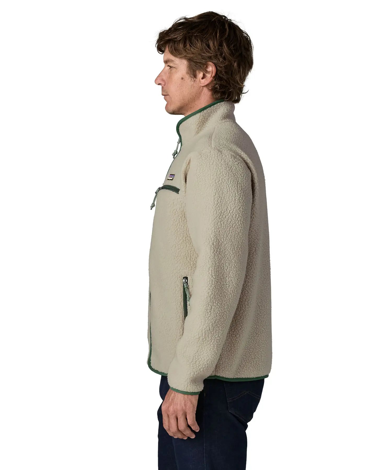 Side of man wearing a Patagonia retro pile jacket in beige with a green trim showing side and chest pockets and stand up collar