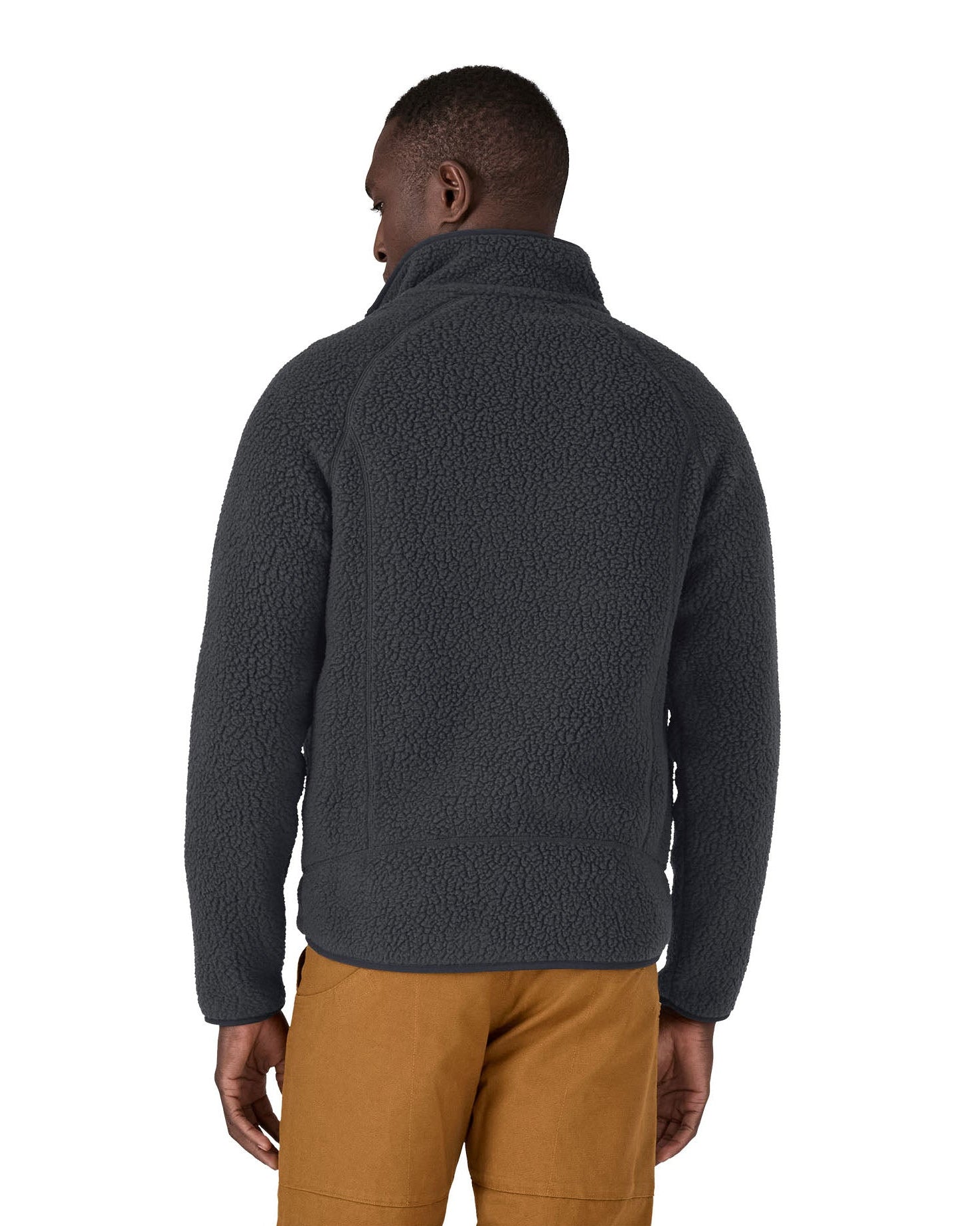 Back of the male in front of a white background wearing brown trousers and a Patagonia thick fleece jacket in black colour with the collar turned up