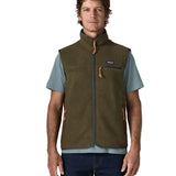 Man wearing Patagonia men's retro pile vest in dark green with a grey trim. Showing front zip fastened. Gilet has a regular fit