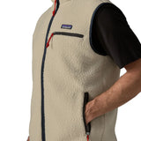 Man wearing Patagonia men's retro pile vest in beige with a navy trim. Showing close up of hand in the side pocket