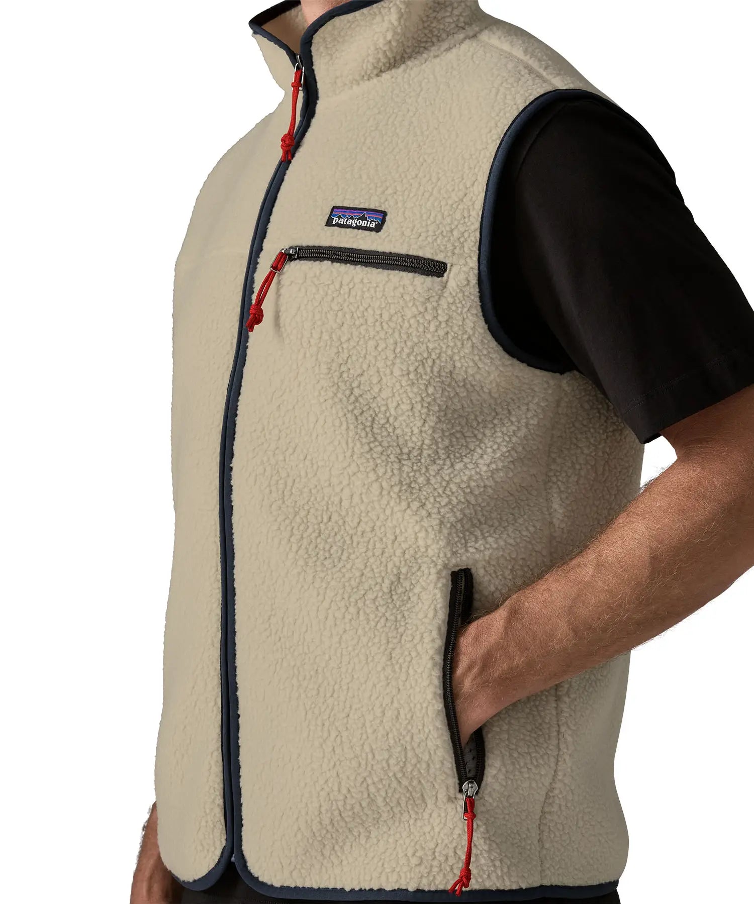Man wearing Patagonia men's retro pile vest in beige with a navy trim. Showing close up of hand in the side pocket