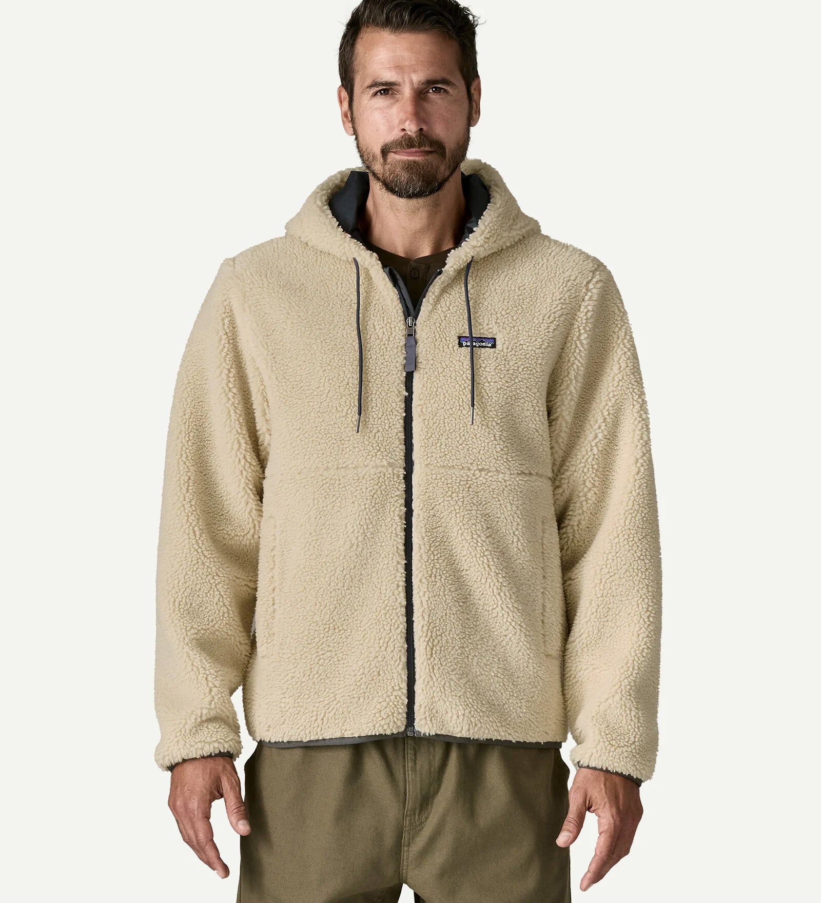 Front three quarter view of a man wearing the Patagonia Men’s Retro-X Fleece Hoody Jacket in Dark Natural, hands in the zippered pockets, showing the full zip and fleece texture.