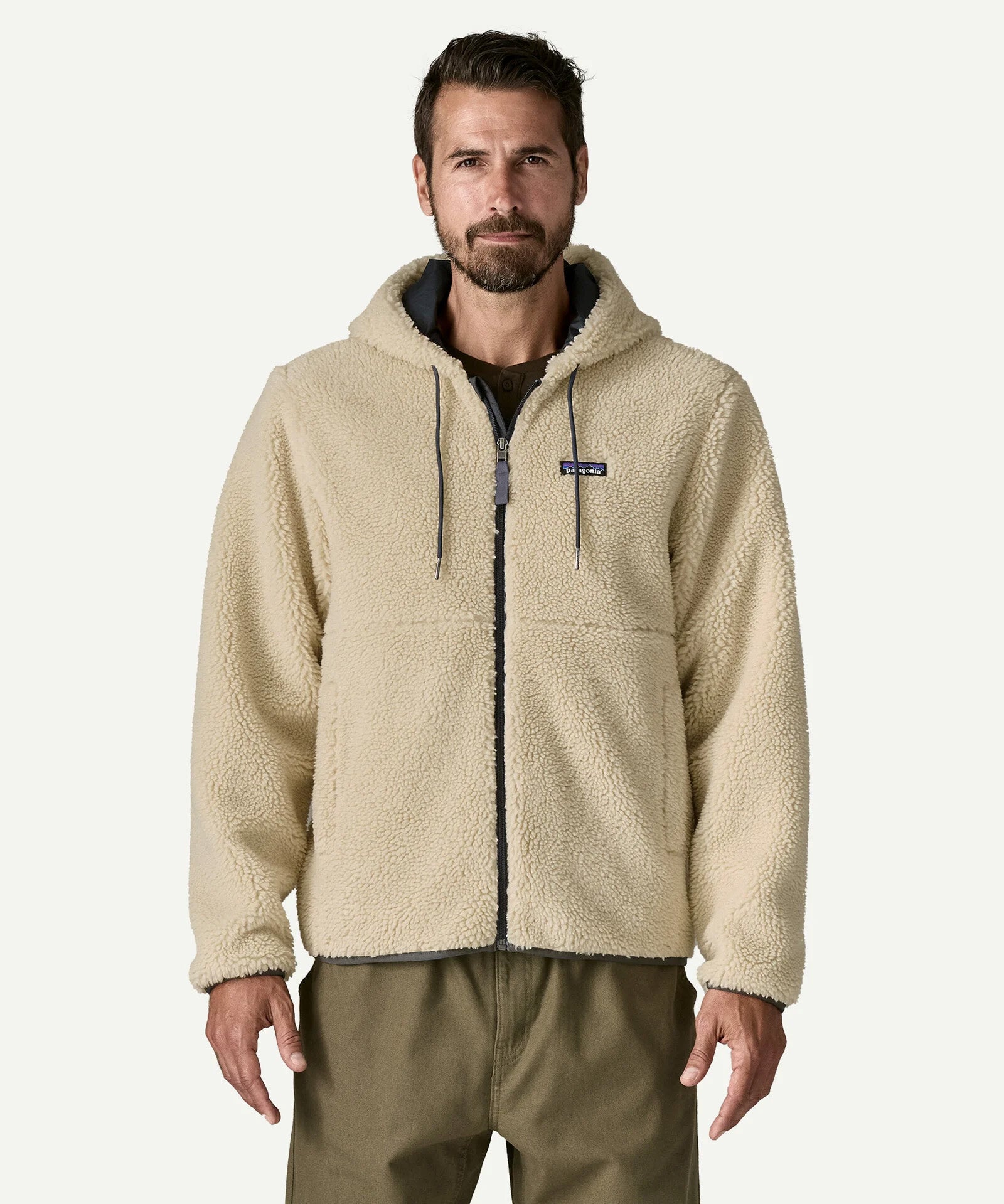 Front three quarter view of a man wearing the Patagonia Men’s Retro-X Fleece Hoody Jacket in Dark Natural, hands in the zippered pockets, showing the full zip and fleece texture.