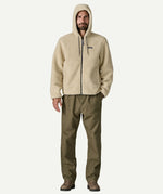 Full front view of a man wearing the Patagonia Men’s Retro-X Fleece Hoody Jacket in Dark Natural, showing the drawcord hood, full length zip and fleece texture.