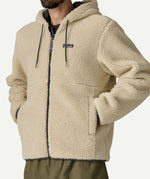 Front portrait of a man wearing the Patagonia Men’s Retro-X Fleece Hoody Jacket in Dark Natural with the hood down, showing the small Patagonia chest logo.