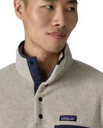 Close up of man wearing Patagonia's synchilla snap t fleece in light grey. Shows the 1/4 length front popper and high neck collar 