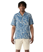 Man wearing Patagonia men's tidal threads camp short sleeve shirt with light blue and cream Hawaiian aloha inspired prints. Shirt has a relaxed fit