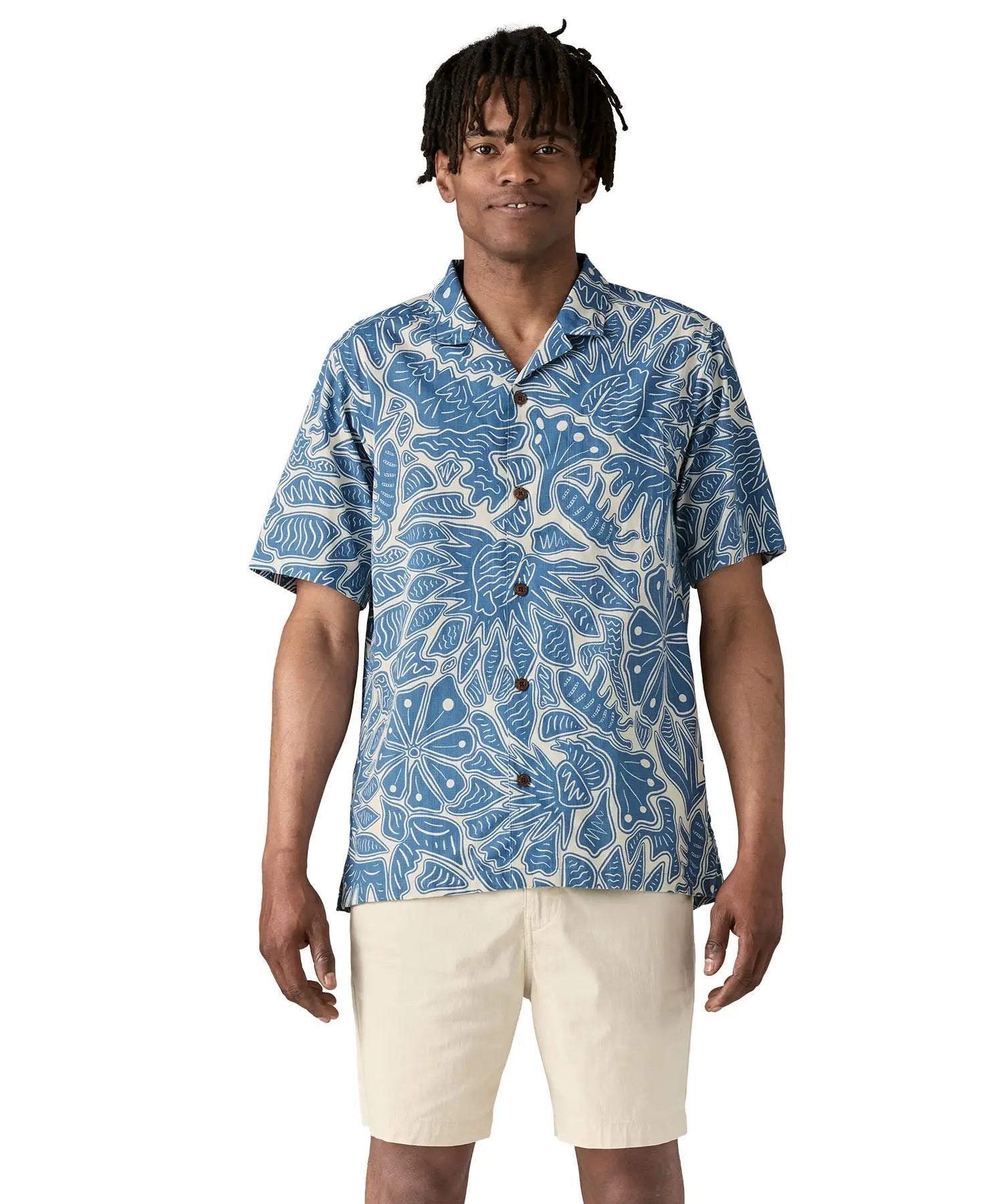 Man wearing Patagonia men's tidal threads camp short sleeve shirt with light blue and cream Hawaiian aloha inspired prints. Shirt has a relaxed fit