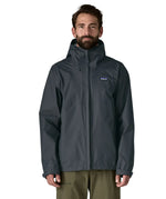 Front of man wearing the Patagonia men's waterproof torrentshell 3 layer rain hooded jacket in smolder blue. Jacket has a relaxed fit