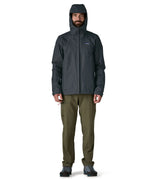 Man wearing the Patagonia men's torrentshell 3 layer rain jacket in smolder blue showing full front zip fastened and hood over the head