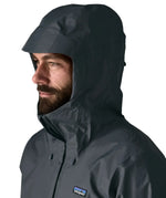 Man wearing the Patagonia men's torrentshell 3 layer rain jacket in smolder blue. Showing close up of adjustable hood over the head
