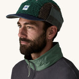 Man wearing Unisex Patagonia Adult Range Earflap Cap in denim, and cascade fleece with flap tied at the top of the head, buy now at Babipur.