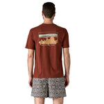 The back of a man wearing the Patagonia Men's 73 Skyline Organic T-Shirt. A brown top with short sleeves with a brand logo in a sketch design printed on the back available at Babipur