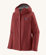 Patagonia Women's Torrentshell 3L Rain Jacket - Oxide Red zipped up the front, on a cream background.