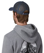 Man wearing Patagonia's p6 logo lopro trucker hat in navy, shows the breathable mesh back panel adjustable strap