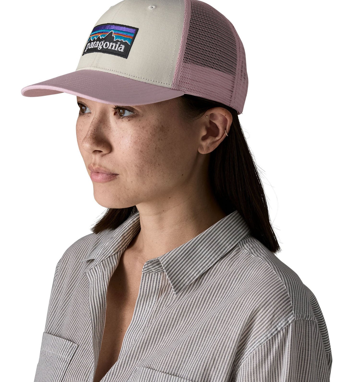 Woman wearing Patagonia's p6 logo trucker hat in white with a pink breathable mesh back panel and visor