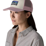 Woman wearing Patagonia's p6 logo trucker hat in white with a pink breathable mesh back panel and visor
