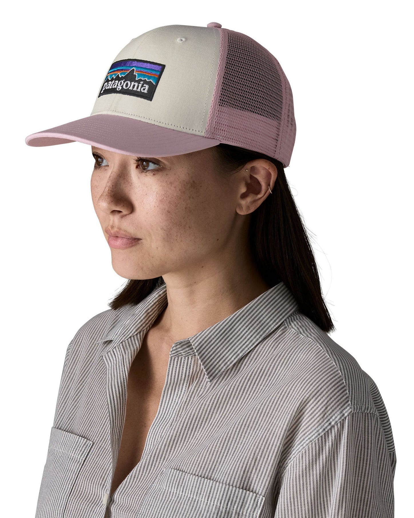 Woman wearing Patagonia's p6 logo trucker hat in white with a pink breathable mesh back panel and visor