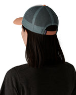 Woman wearing Patagonia's p6 logo lopro trucker hat in white, shows the light blue breathable mesh back panel adjustable strap