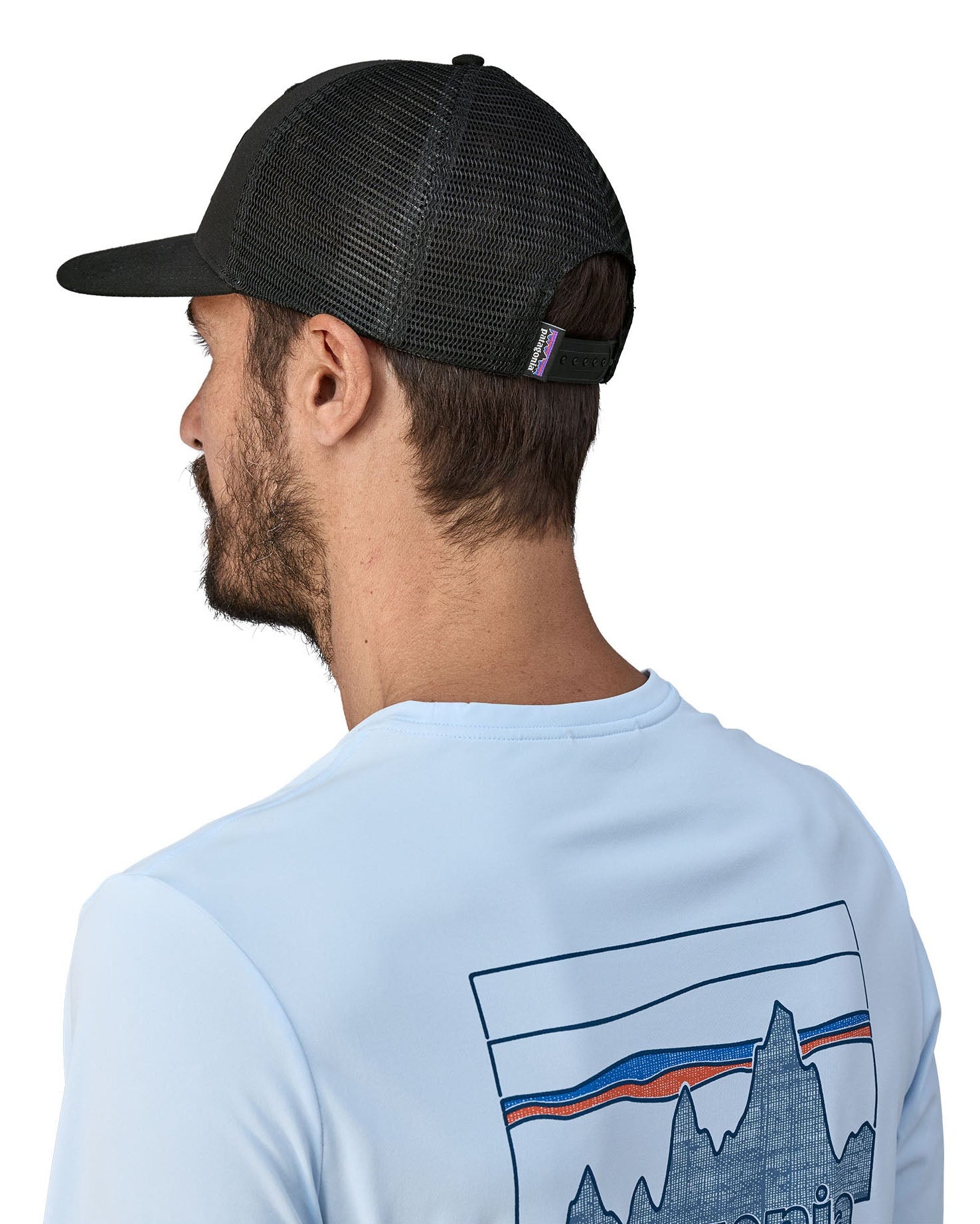 Man wearing Patagonia's logo trucker hat in black shows the breathable mesh back panel and adjsutable strap