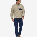 An adult wearing the Patagonia Men's Synchilla Snap-T Fleece - Oatmeal Heather, and blue jeans