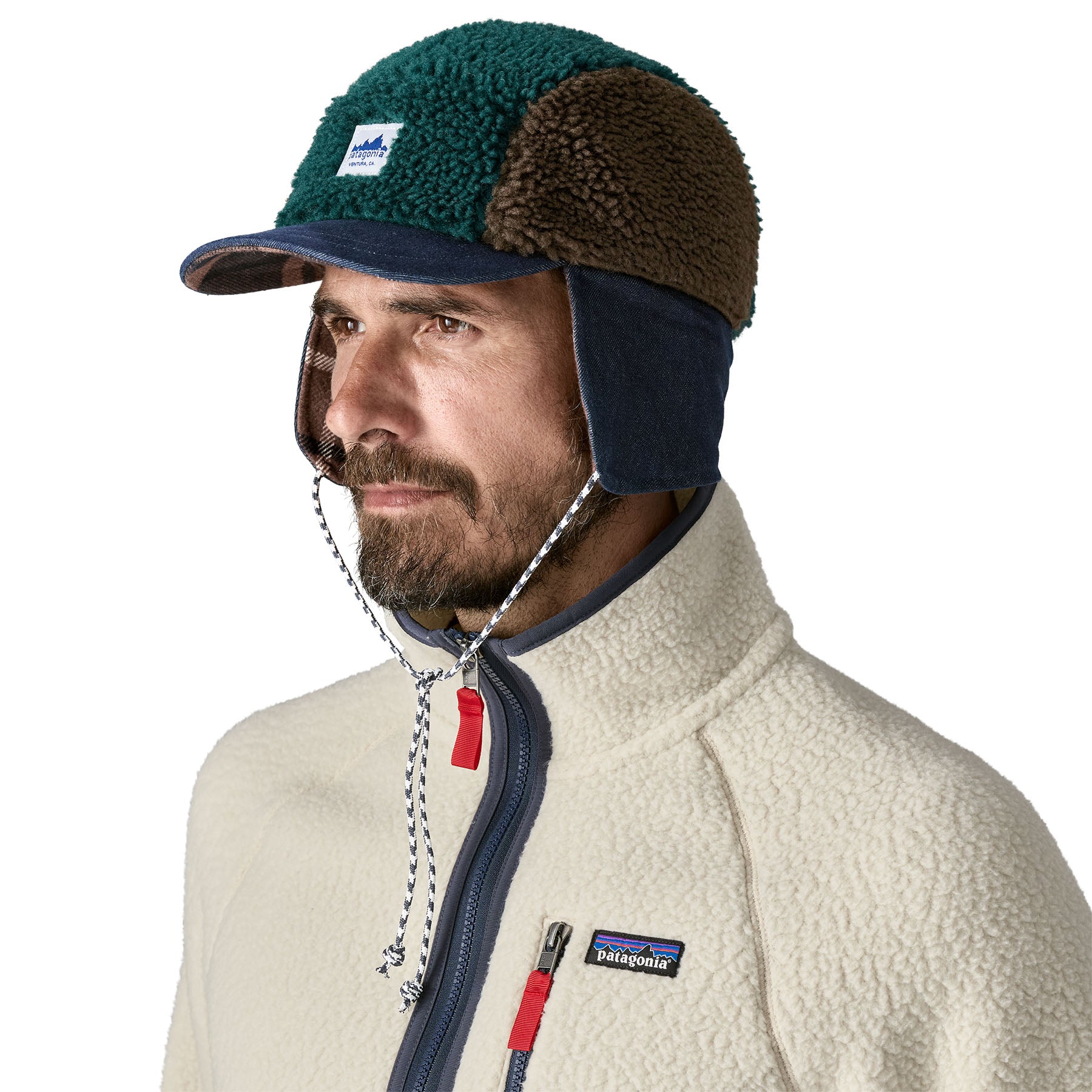 An man wearing the Patagonia adult range cap in cascade green available at Babipur. Showing ear flaps down and tied together