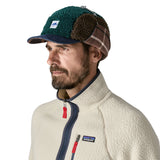 An man wearing the Patagonia adult range cap in cascade green available at Babipur. Showing ear flaps tied up 