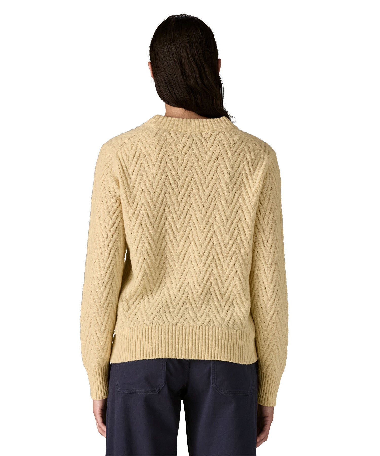 The back of a woman wearing the Patagonia Women's cream Recycled Wool-Blend Crewneck Sweater in chevron cable available at Babipur.