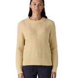 A woman wearing the Patagonia Women's Recycled Wool-Blend Crewneck Sweater - in dark natural colour available at Babipur.. A heavy knitted  jumper with a chevron style design 