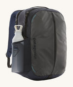 The Patagonia Refugio Day Pack 26L  Smolder Blue, with a water bottle in the mesh side pocket
