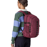 Back of woman carrying a Patagonia's 30L refugio backpack in maroon on the shoulders showing mesh side pockets and brown gear loops