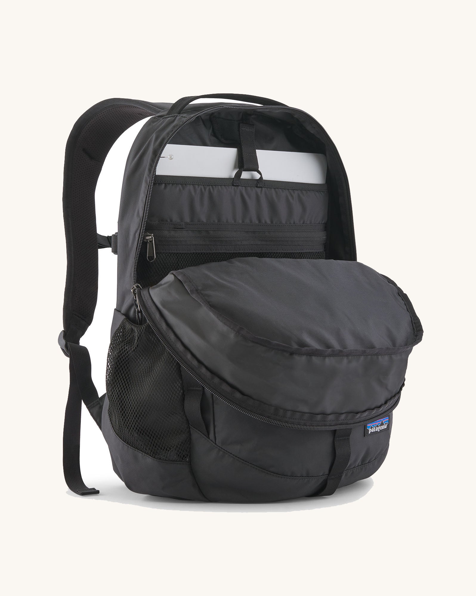 Patagonia refugio 26L back pack in black with the main compartment open and a laptop in the sleeve at the back.