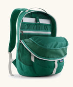 Patagonia refugio 26L back pack in green with the main compartment open and a laptop in the sleeve at the back.