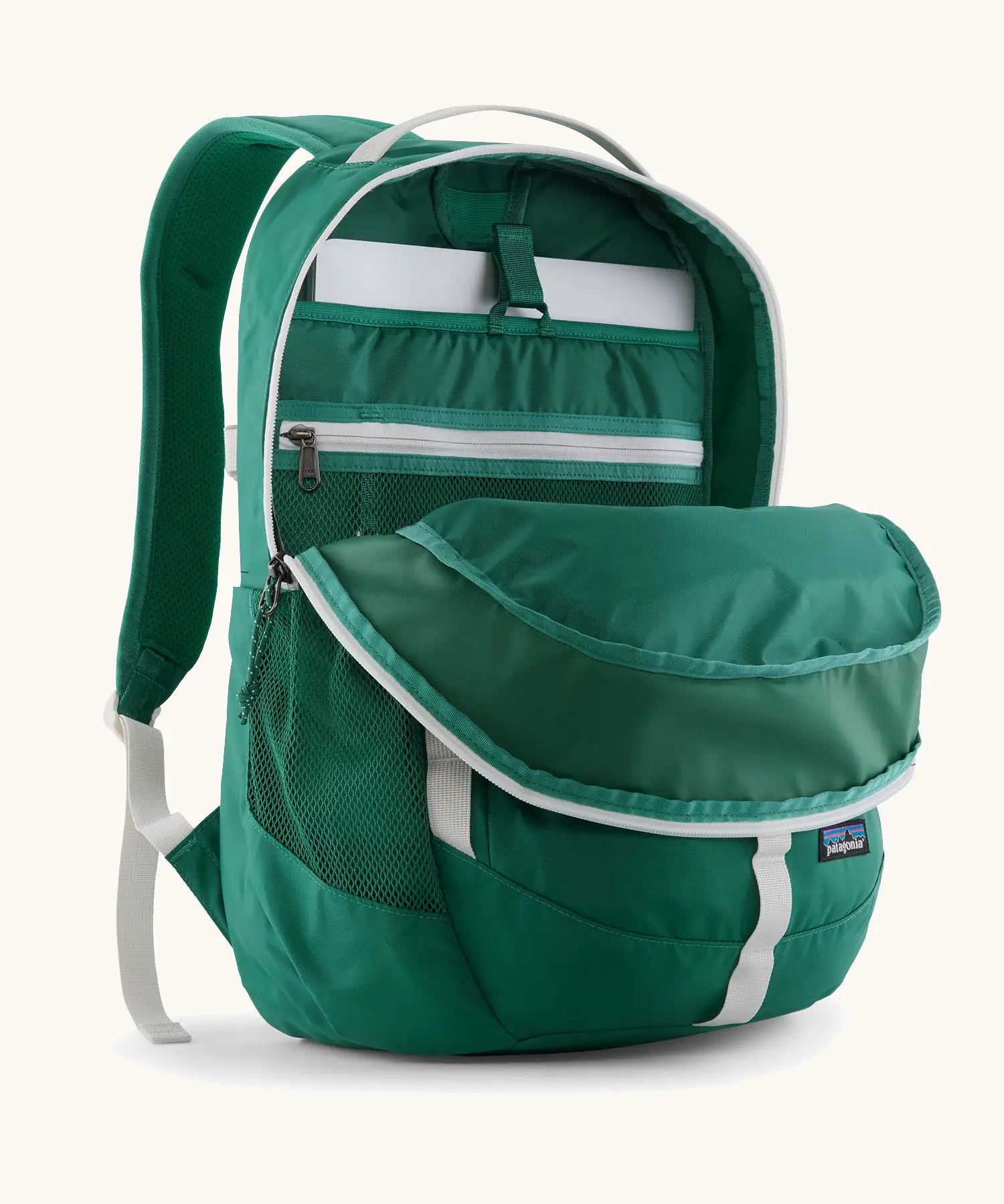 Patagonia refugio 26L back pack in green with the main compartment open and a laptop in the sleeve at the back.