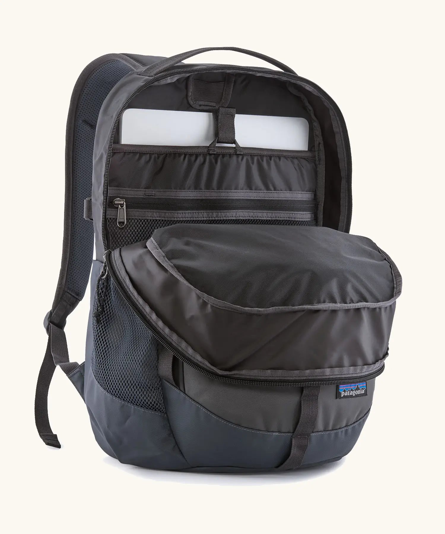 Patagonia refugio 26L back pack in dark blue with the main compartment open and a laptop in the sleeve at the back.