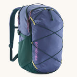 Patagonia refugio 30 litres day pack in current blue. A 100% recycled material backpack in dark blue with dark green, yellow and pink detail. Features padded shoulder pads, mesh side pockets and a bungee cord on the front to keep items secured