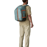 Back of man wearing a full Patagonia's refugio 32L daypack in sage blue with orange trim 