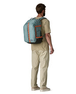 Back of man wearing a full Patagonia's refugio 32L daypack in sage blue with orange trim 