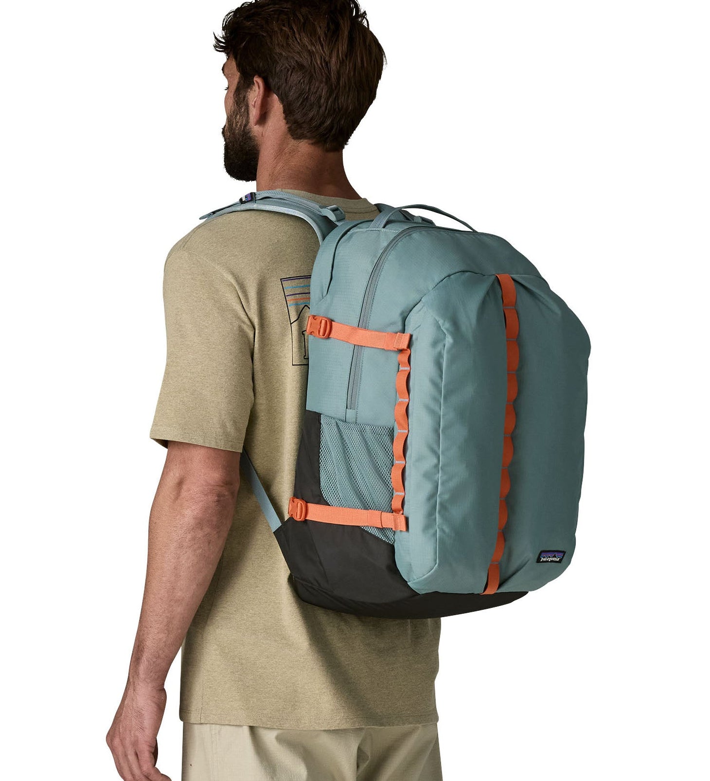 Back of man wearing Patagonia's refugio 32L daypack in sage blue with orange trim showing the mesh side pocket