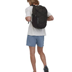 A person wearing the Patagonia Refugio Day Pack 30L Black, showing the back pack from the front