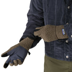 An adult putting on the Patagonia adult synchilla gloves in marlon brown available at Babipur. 