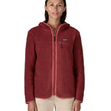 A woman wearing the A Patagonia Women's Retro Pile Fleece Hoody Jacket in the Sequoia Red colour way available at Babipur. The dark burgundy red, zipped, hooded ladies fleece has handy zipped pockets.