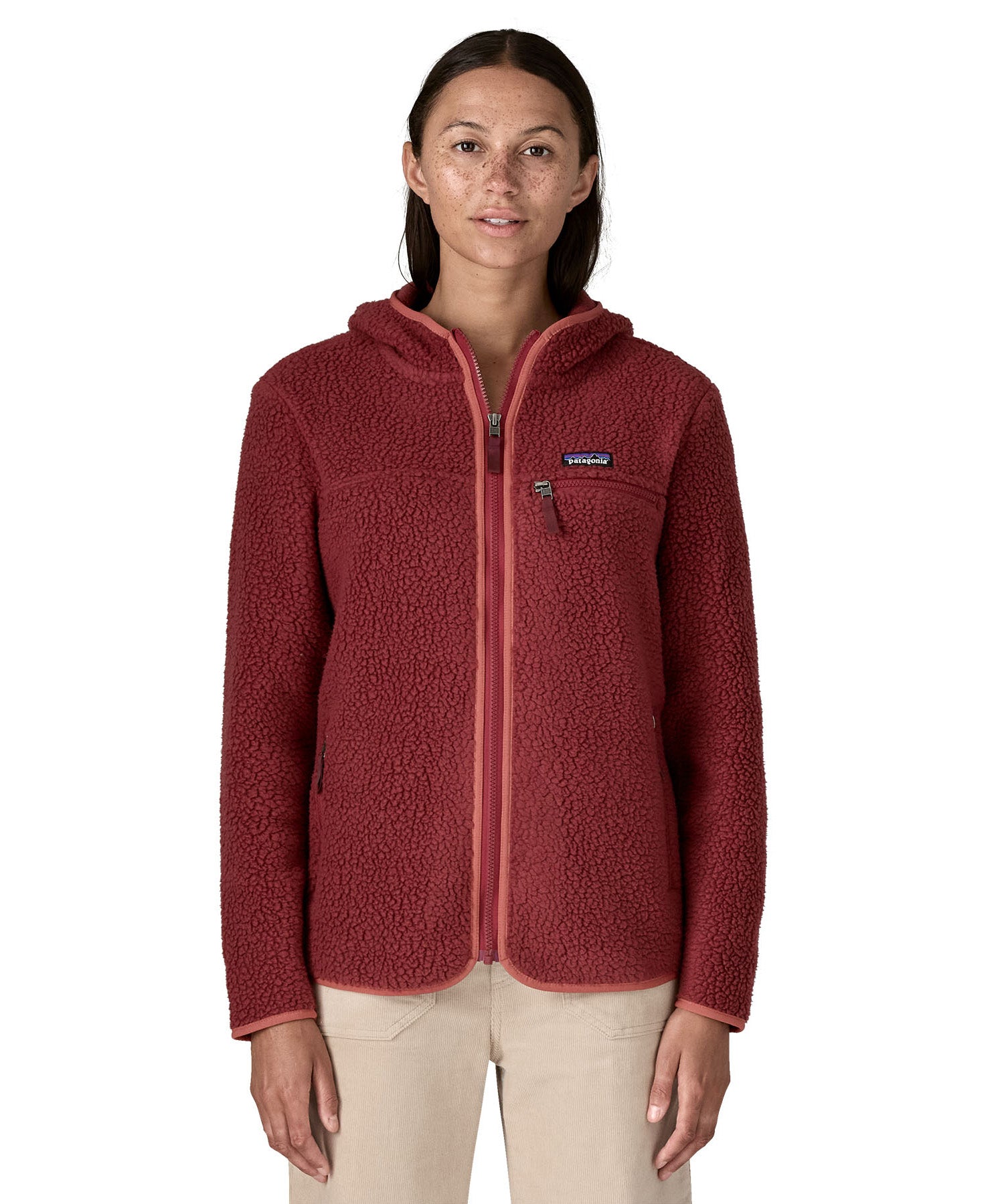 A woman wearing the A Patagonia Women's Retro Pile Fleece Hoody Jacket in the Sequoia Red colour way available at Babipur. The dark burgundy red, zipped, hooded ladies fleece has handy zipped pockets.