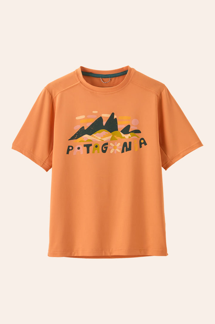 Patagonia kids t-shirt in organic cotton with the Patagonia name and mountains  and flowers in earthy tones. the t shirt is orange. 